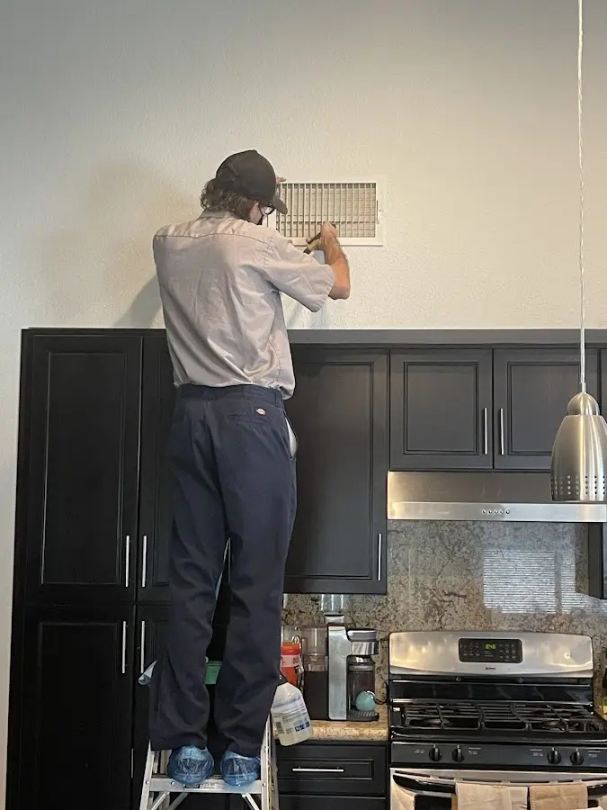 Technician inspecting an air vent during HVAC service in Eaton
